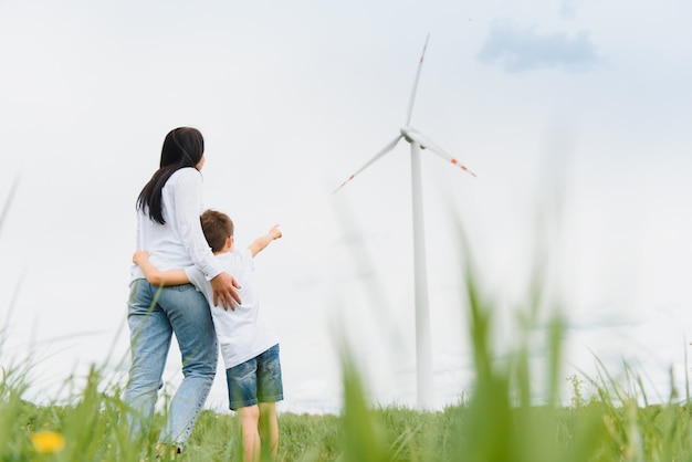 Energía alternativa, parque eólico y tiempo feliz en familia. Madre feliz en el camino con su hijo de vacaciones y escapar a la naturaleza.