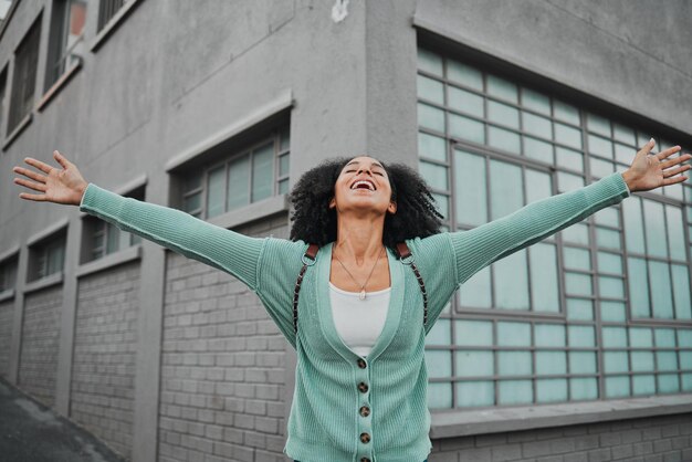 Energía feliz y sonrisa con mujer negra en celebración del éxito ganando y animando en la ciudad de Nueva York Motivación libertad y alegría niña en la ciudad vacaciones y celebrar la victoria por construcción urbana