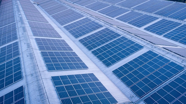 Energia verde futura e conceito de recurso de eletricidade sustentável Foco ao ar livre em painéis solares em telhados ou fotovoltaicos de fábricas por drone Telhado industrial com grade de células solares com tom azul