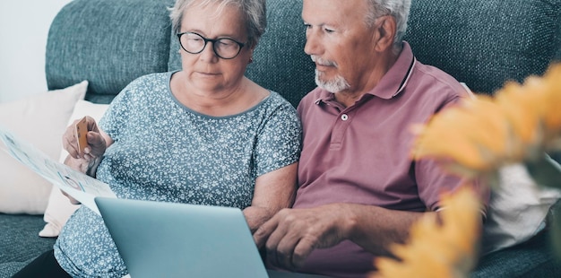 Energiegasrechnungen kosten Probleme im Lebensstil älterer Menschen Ein besorgtes Paar von Senioren zu Hause, das Laptops benutzt, um Rechnungen zu bezahlen und Dokumente zu überprüfen Reifer Mann und Frau mit Computer und Online-Zahlungsbanking