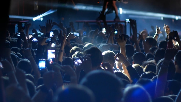 Energiegeladene Menschen tanzen mit erhobenen Händen bei der blauen Beleuchtung des Punkkonzerts