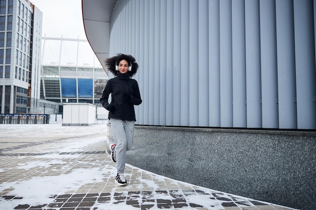 Energiegeladene Sportlerin läuft am Gebäude entlang