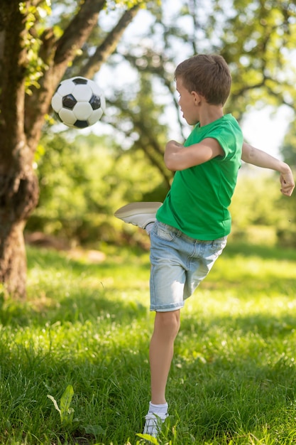 Energischer Junge, der Fußball zurück tritt.