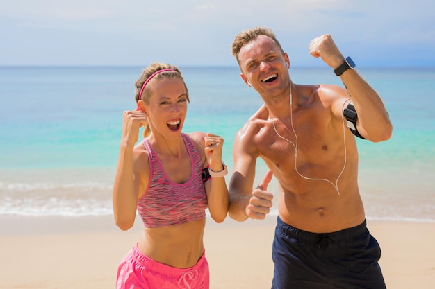 Energisches Paar, das das erreichte Fitnessziel am Strand feiert
