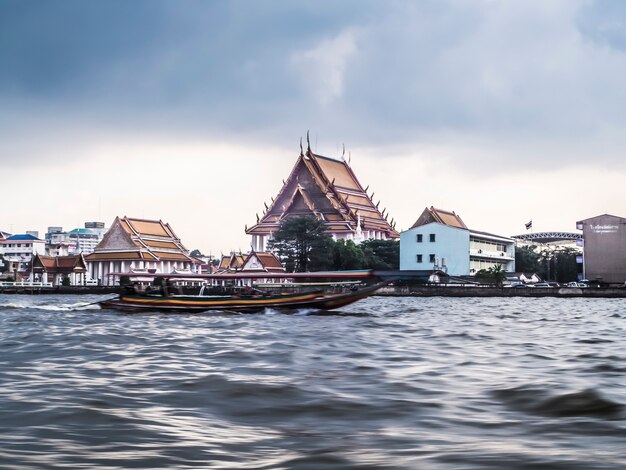 Enero de 2019, Bangkok, Tailandia, el río de Bangkok y el edificio rascacielos rascacielos paisaje urbano paisaje fluvial taxi barco sirven para el transporte público fondo del templo de la ciudad vieja