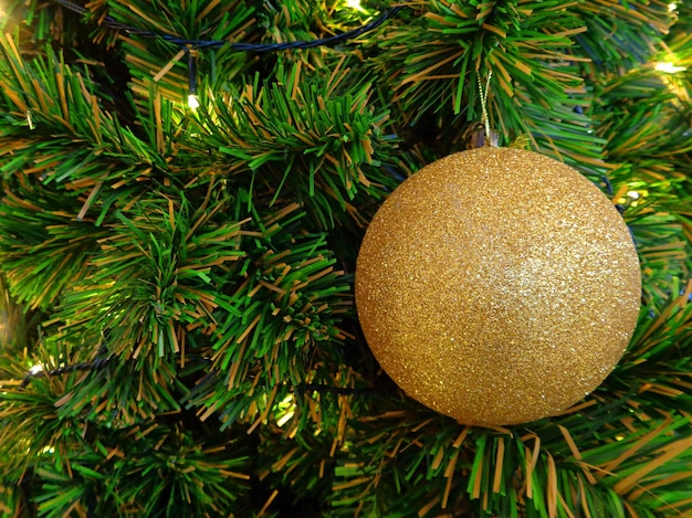 Enfeite de bola de glitter dourado na árvore de Natal