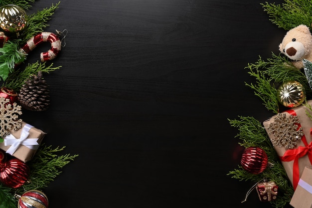 Enfeites de Natal, caixas de presentes, pinha, ursinho de pelúcia e decoração de galhos de árvore do abeto em fundo escuro.