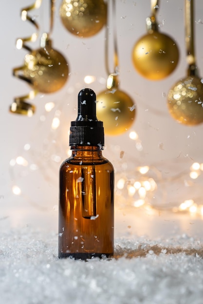 Enfeites de natal dourados no fundo brilhante brilhante recipiente cosmético com conta-gotas e soro conceito de cosméticos de ano novo