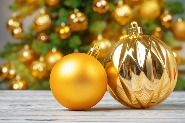 Enfeites de Natal em uma mesa de madeira contra uma árvore de Natal decorada. Fundo desfocado