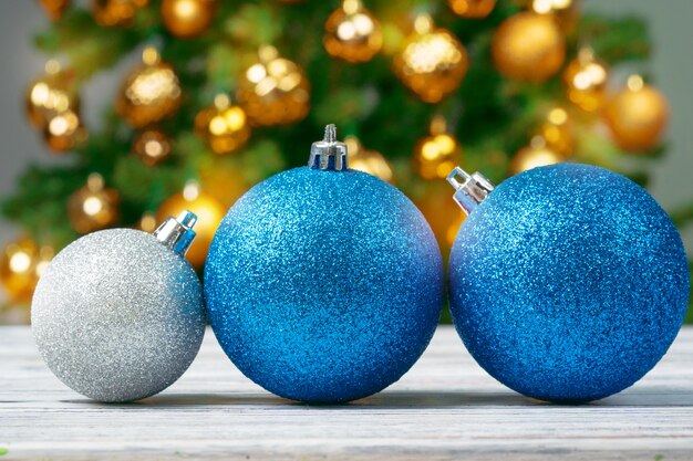 Enfeites de Natal na mesa de madeira contra o fundo desfocado da árvore de Natal decorada