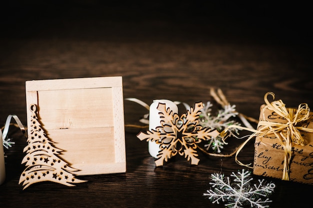 Enfeites para árvores de natal, presente, caixa com fitas, flocos de neve, velas em um fundo de madeira estrutural marrom. vista lateral, moldura com espaço para texto. boas festas. feliz natal, conceito de ano novo.