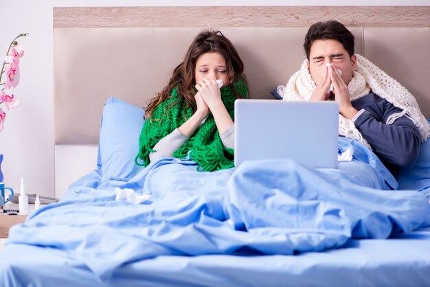 Enferma esposa y esposo en la cama con laptop