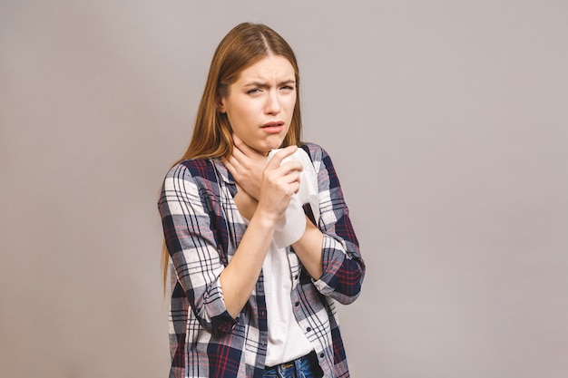 Enferma joven rubia en casual con dolor de garganta, con la mano en el cuello. Dolor de garganta, doloroso concepto de deglución.