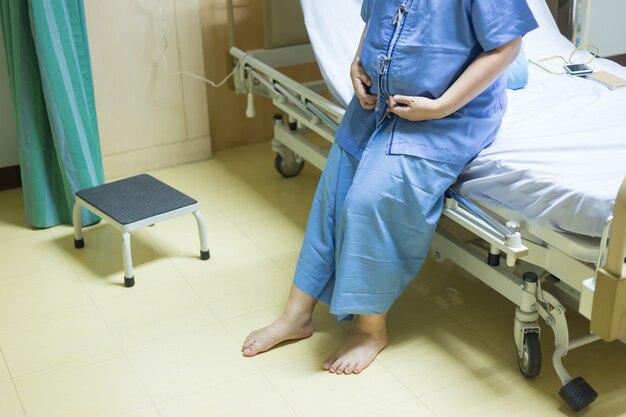 Enfermedad de las mujeres pacientes en la cama viendo ventanas en la habitación sola del hospital y copyspace