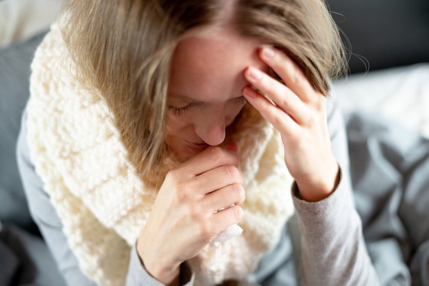 Enfermedad. Tratamiento a domicilio. La gripe y el resfriado común. Una mujer está enferma en casa, moqueo nasal y gripe.