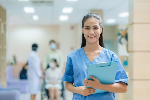 Foto enfermeira asiática de uniforme trabalhando no hospital com médico e paciente em cadeira de rodas