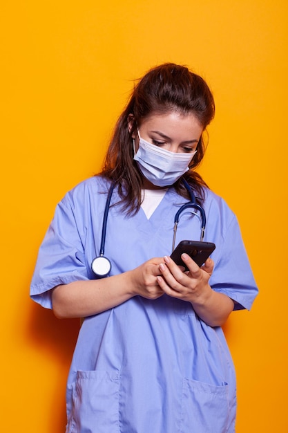 Enfermeira caucasiana olhando para smartphone com tecnologia