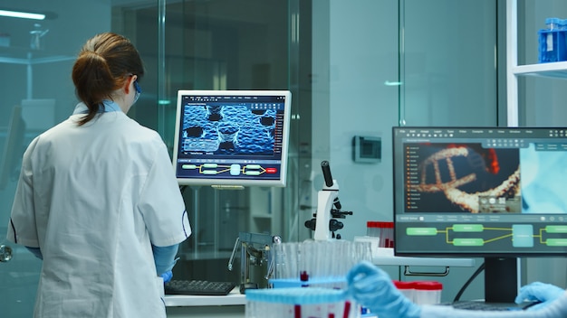 Enfermeira cientista digitando relatórios médicos no computador em um laboratório científico moderno equipado. examinando a evolução da vacina usando alta tecnologia e pesquisa de tratamento contra o vírus covid19