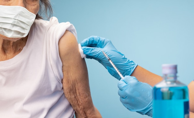 Enfermeira closeup fazendo injeção de vacina para mulher sênior.
