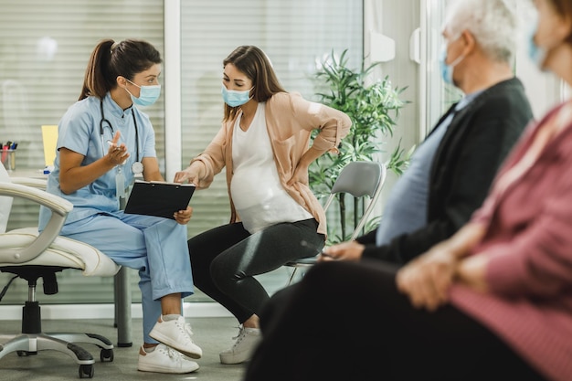 Enfermeira conversando com jovem grávida antes da vacina covid-19 na sala de espera do hospital.