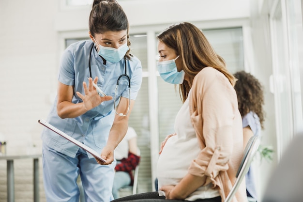 Enfermeira conversando com uma jovem grávida e analisando o relatório médico antes da vacinação contra o coronavírus.