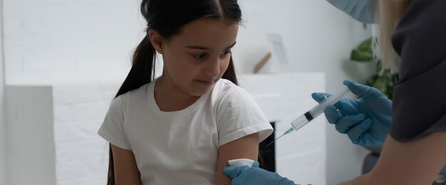 Enfermeira dando injeção de vacinação para paciente menina.