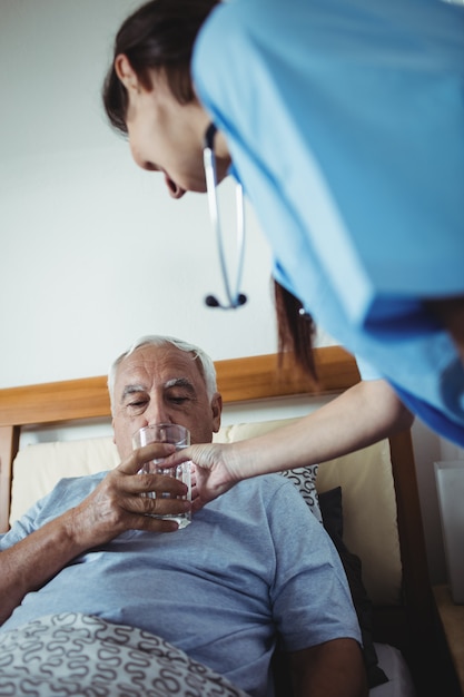 Foto enfermeira dando um copo de água para homem sênior