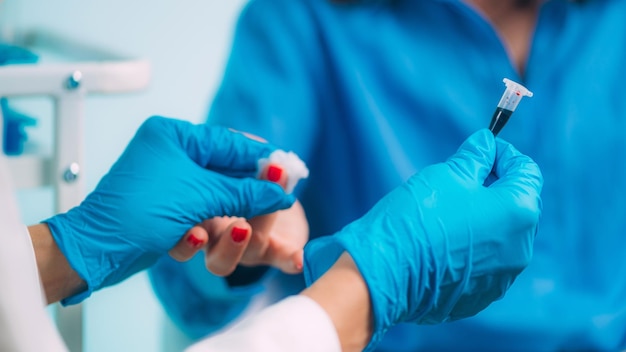 Foto enfermeira de coleta de sangue com picada no dedo coletando amostra de sangue do dedo do paciente