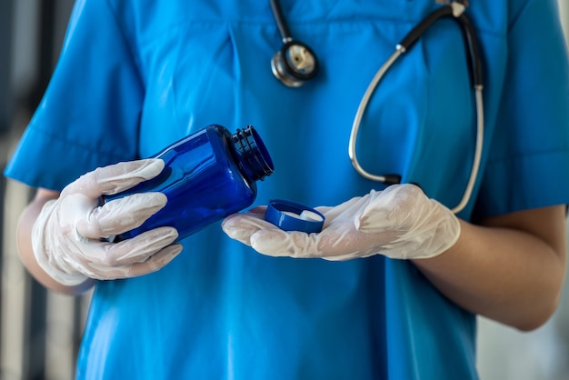 Enfermeira de uniforme azul, segurando o frasco com comprimidos brancos. conceito médico