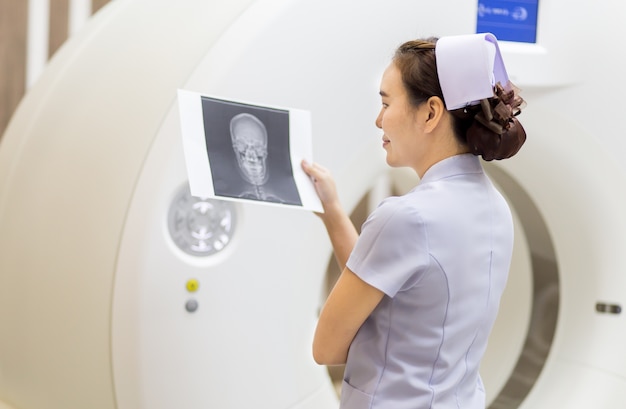 Foto enfermeira e imagem de crânio de raio-x na sala de tomografia computadorizada