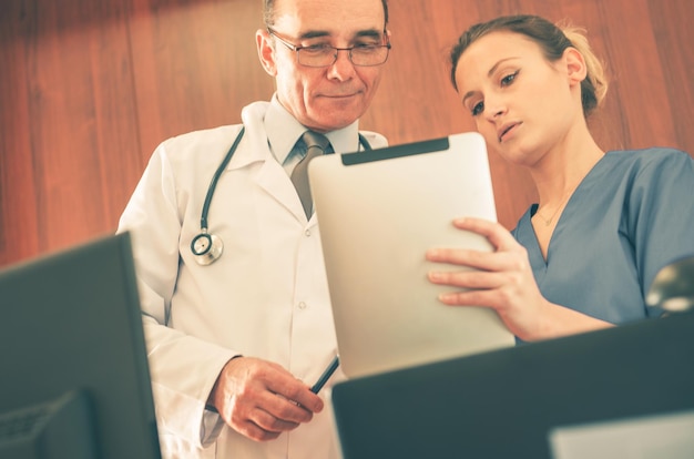 Enfermeira e médico olhando para as informações médicas do paciente