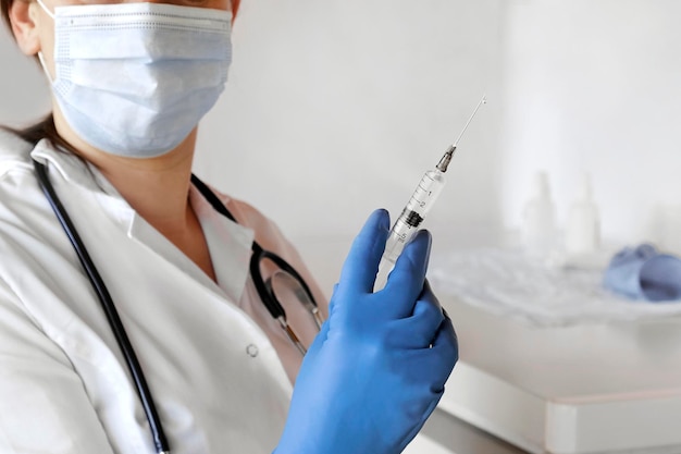 Enfermeira empurrando o ar para fora da seringa para injeção de vacina Médico usando luvas azuis e máscara médica Pessoa segura uma seringa com remédio na mão Close Up Ela está pronta para dar uma injeção Ciência