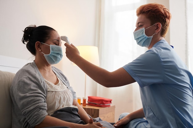 Enfermeira examinando paciente doente na cama