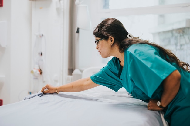 Foto enfermeira fazendo a cama em um hospital