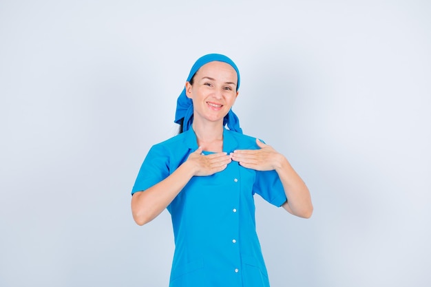 Enfermeira feliz sorridente está juntando as mãos no peito no fundo branco