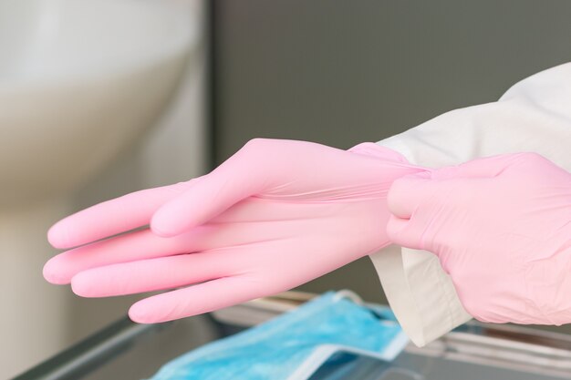 Foto enfermeira mãos calça luvas cor de rosa no hospital close-up.