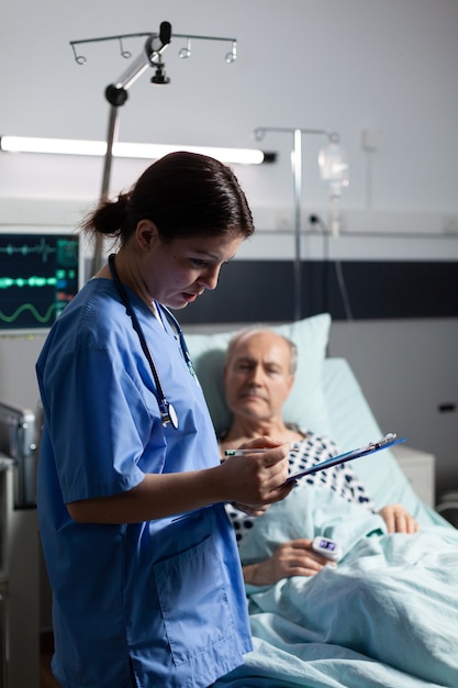 Enfermeira médica em scrubs fazendo anotações no cliboard