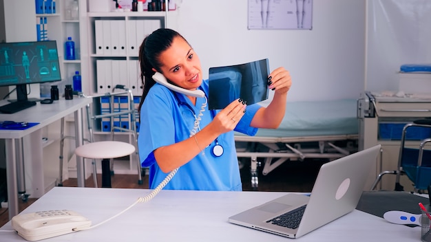 Enfermeira médica falando ao telefone com o paciente analisando as radiografias, discutindo o diagnóstico, marcando a consulta. Terapeuta, assistente médico ajudando na comunicação de telessaúde, consulta