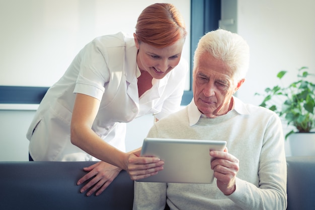 Enfermeira mostrando relatório médico para homem sênior no tablet digital