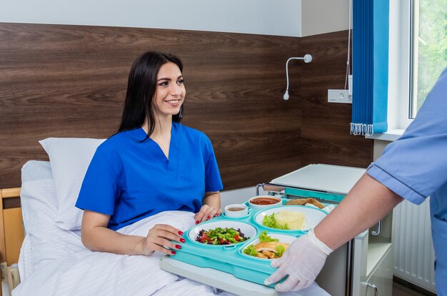 Foto enfermeira no casaco médico está segurando uma bandeja com café da manhã