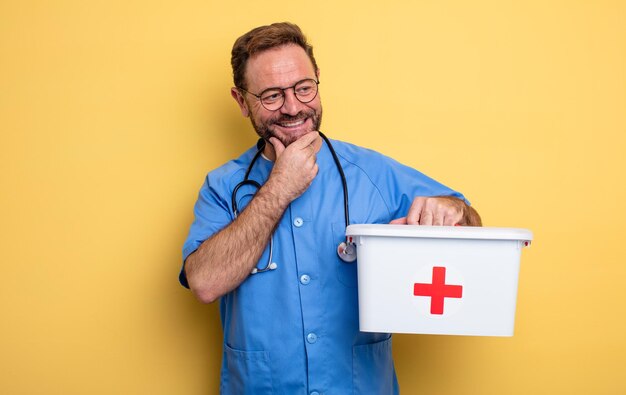 Enfermeira ou médico sorrindo com uma expressão feliz e confiante com a mão no queixo conceito de negócios e telefone conceito de kit de primeiros socorros