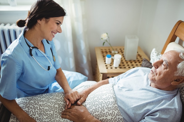 Foto enfermeira, segurando as mãos do homem sênior