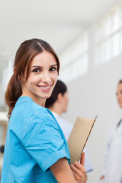 Foto enfermeira sorridente enquanto segura arquivos e está de pé com um médico e um paciente