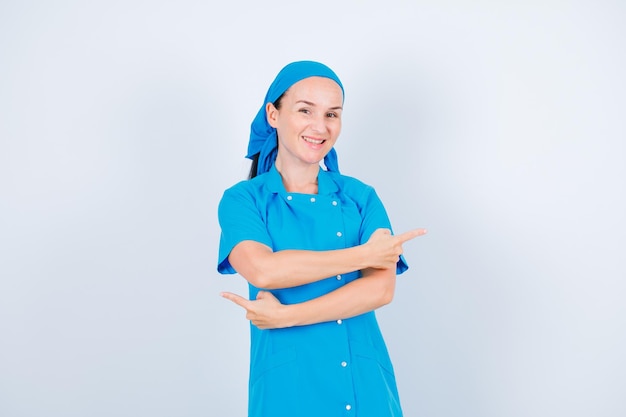 Enfermeira sorridente está apontando para a direita e para a esquerda com os dedos indicadores no fundo branco