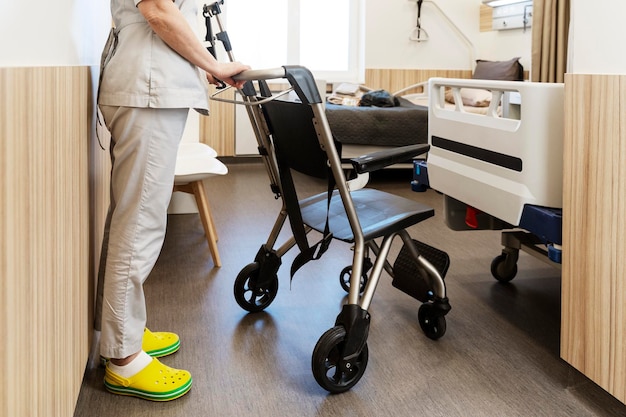 Enfermeira trouxe uma cadeira de rodas para um elegante quarto de hospital O conceito de movimento confortável para atendimento ao paciente