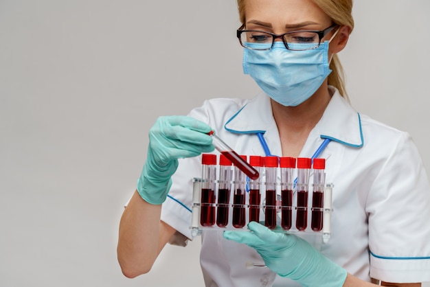 Foto enfermeira usando máscara protetora e luvas e segurando o suporte com exames de sangue do vírus