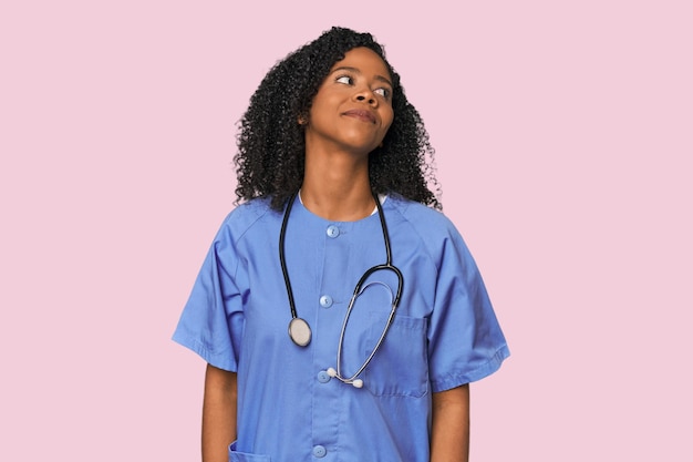 Enfermera afroamericana en el fondo del estudio soñando con lograr metas y propósitos