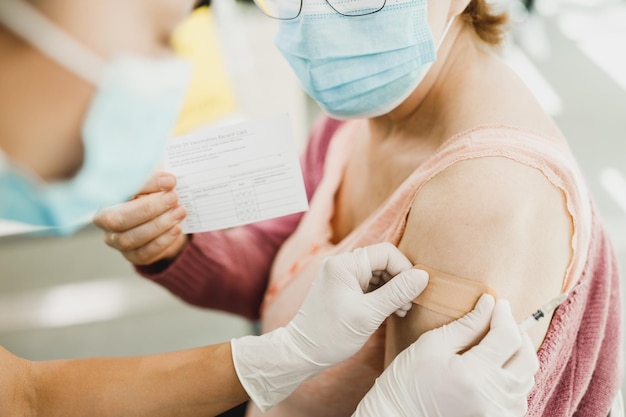 Una enfermera aplicando una tirita a una anciana después de recibir una vacuna debido a la epidemia de coronavirus.