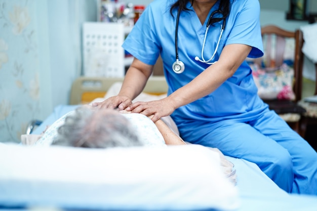 Enfermera asiática, fisioterapeuta, médico, ayuda y apoyo a una anciana o anciana anciana, paciente, acostado en la cama en la sala del hospital.