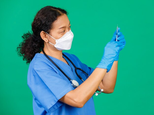 Foto enfermera asiática en matorrales con máscara con jeringa y vacuna covid 19 preparándose para la inyección. concepto de vacunación contra covid 19.